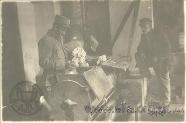 Μακαρονοποιείο του ελληνικού στρατού σε χώρο όπου παλαιότερα στεγαζόταν αρμένικος κινηματογράφος. Ο Καλοχαιρέτας, πατέρας του ιδιοκτήτη μηχανουργείου στη Σμύρνη, παρακολουθεί στρατιώτες που χειρίζονται μηχανές παρασκευής ζυμαρικών. Μικρασιατική εκστρατεία.