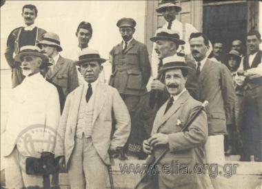 Minister for Social Relief Spyridon Simos and civilians at the entrance to a building