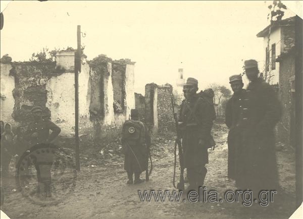Balkan Wars. - Greek  soldiers in a city street. Behind them, houses destroyed by retreating Turks