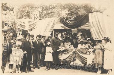 Stand with Greek  products in an international bazaar (?) probably in Smyrna. A Greek  military officer  poses in front of the stand.