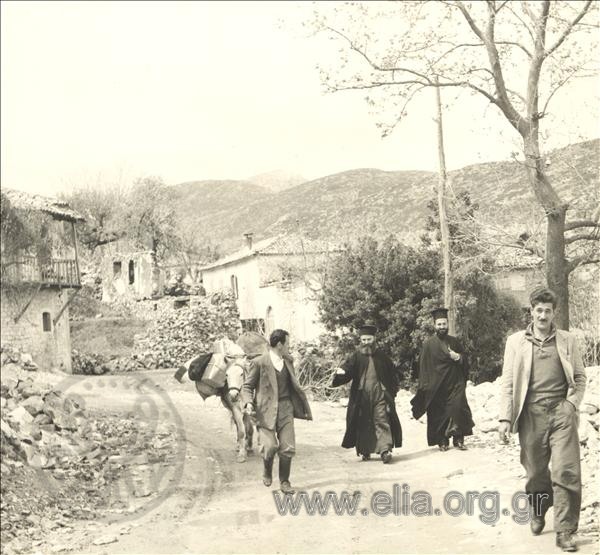 Trader or pack animal driver and priests on a street of town