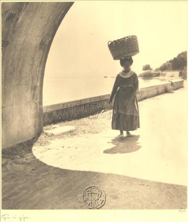 Κερκυραία, με κοφίνι στο κεφάλι, κατευθύνεται στην πόλη της Κέρκυρας.