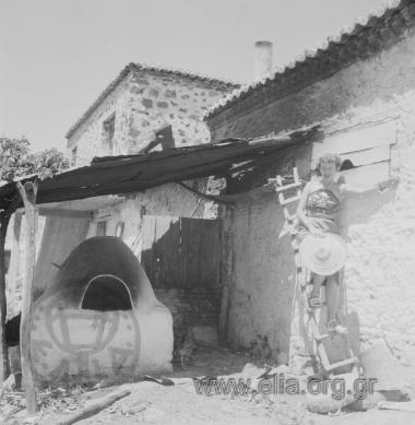 Τουρίστρια ποζάρει πάνω σε ξύλινη σκάλα δίπλα στον κτιστό φούρνο.