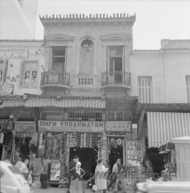 Οδός Αθηνάς (αρ. 32-34). Τα καταστήματα υποδημάτων Μουρούτη (34) και Περικλή Φραγκούλη (32), ηλεκτροκίνητο τορνευτήριο Δ. Τζίτζη, καταστήμα κορνιζών/καθρεπτών Τσιάτα και ηλεκτρικών συσκευών (;) Μακρή.