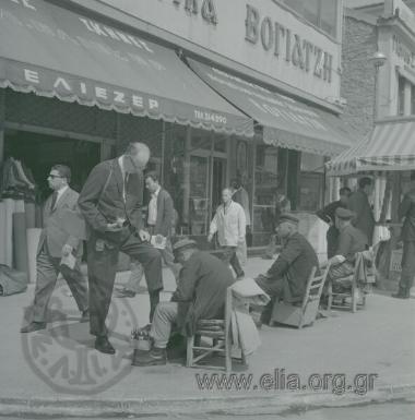 Λούστροι έξω από τα καταστήματα Βογιατζή (εκκλησιαστικά είδη) και Ελιέζερ (είδη camping - σκηνές).