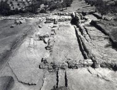 Άσπρα Χώματα. Γενική άποψις βοηθητικού κτηρίου με το λιθόστρωτο και υπολείμματα βωμών και το ανατολικό σκέλος - στοά σε πρώτο επίπεδο, το γωνιαίο δωμάτιο και το βόρειο σκέλος στο βάθος.
