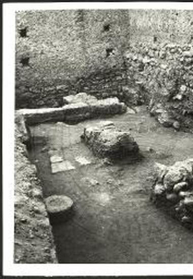 Η ΝΑ. γωνία του αποκαλυφθέντος ΥΜ ΙΙΙΒ δωματίου. Το τμήμα του συγχρόνου του δωματίου τοίχου και εις το βάθος ο ΜΜ ΙΙΙΒ-ΥΜ ΙΑ τοίχος. Αριστερά η βάσις του κίονος (Φωτ. από ΒΑ).