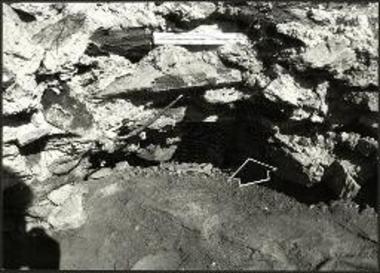 Η ταφή ανάμεσα στη μάζα της χυτής τοιχοποιίας του ακρόπυργου Π1 (η θέση σημειώνεται με βέλος).