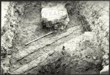 Οικόπεδο Στυλιανουδάκη. Τάφρος 2. Η πάνω επιφάνεια του αγωγού και το θεμέλιο του τοίχου 5 (από Β).