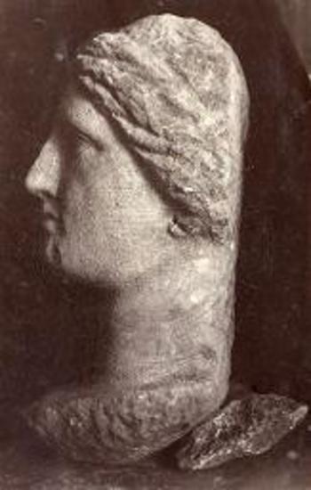 Άποψις της κεφαλής μετά λαιμού και μέρους του στήθους αγάλματος γυναικός. Παρίου μαρμάρου. Εκ φωτογραφίας γενομένης ευθύς μετά την εύρεσιν, προ του καθαρισμού. Εκ του ιερού της Πασικράτας.