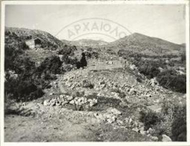 Το τοπίον του Σκλαβοκάμπου κατά την χάραξιν της οδού, προ της ενάρξεως της ανασκαφής. Εις το βάθος το χωρίον Γωνιές.