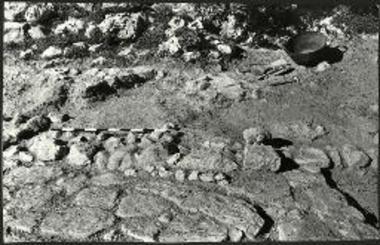 Το βόρειον άκρον του βαθμιδωτού πλακοστρώτου 44, τοίχος - βαθμίς (όπου ο δείκτης) και λείψανα λιθοστρώτου υπό την θεμελίωσιν του Κυκλωπείου, από Ανατολών (1972).