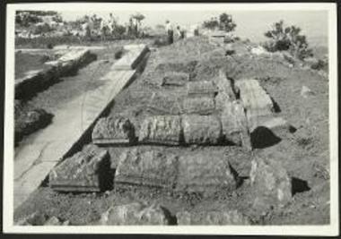 Κατακεκλιμένοι κίονες παρά την ανατολικήν πλευράν του ναού ως αρχικώς ευρέθησαν. Όψις από Νότου. Διακρίνονται σαφώς αι υπό του αρότρου προξενηθείσαι φθοραί.