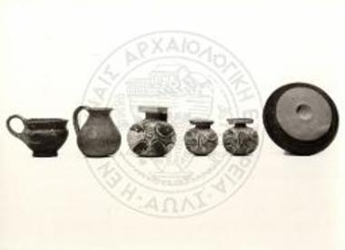 Ε9/β. Βοιωτικό μελαμβαφές κύπελλο (αρ. 15631). Μικρή αβαφής όλπη (αρ. 8863). Τρείς σφαιρικοί αρύβαλλοι με τετράφυλλο και δικτυωτούς ρόμβους.