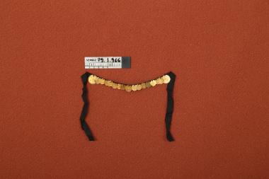 Κόσμημα με φλουριά - νομίσματα οθωμανικά (17), χάλκινα, επίρραπτα κατά μήκος σε ταινία βαμβακερή μαύρη, μακρόστενη