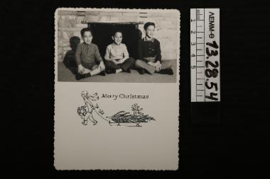 Ευχητήρια κάρτα - χριστουγεννιάτικη, με ασπρόμαυρη φωτογραφία στην οποία απεικονίζονται τρία παιδιά μπροστά από το τζάκι, 1959
