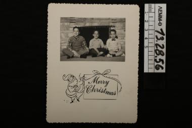 Ευχητήρια κάρτα - χριστουγεννιάτικη κάρτα με ασπρόμαυρη φωτογραφία στην οποία απεικονίζονται τρία παιδιά μπροστά από το τζάκι, 1958