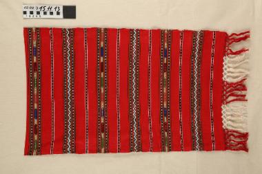 Πετσέτα - υφαντή, βαμβακερή πετσέτα σε κόκκινο χρώμα με πολύχρωμες ρίγες και πλεκτά κρόσσια στις στενές πλευρές, δεκαετίας 1930