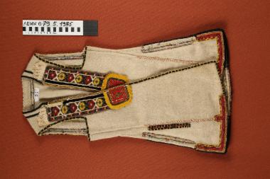 Επενδύτης - μάλλινος, αμάνικος, παιδικός σαγιάς, σε υπόλευκο χρώμα διακοσμημένο με κεντημένες υφαντές κορδέλες με πολύχρωμα γεωμετρικά μοτίβα