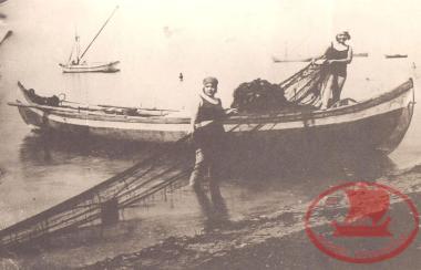 Summer at Aretsou Beach. Young women in their swimsuits pull up the nets on the Sia fishing boat during the Interwar years