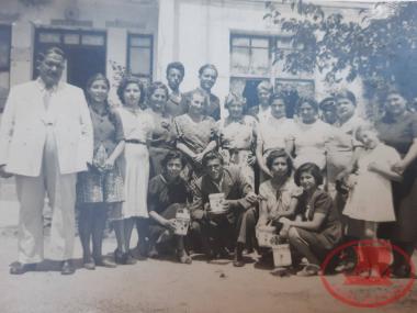 Sakaris with a group of men, women, and girls in the yard of the 
