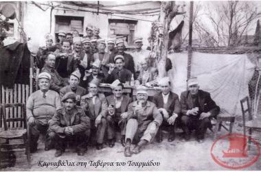 The residents of Aretsou are celebrating Carnival Day at the Tavern of Tsarmados, located at the intersection of Karamaouna and Drakopoulou streets