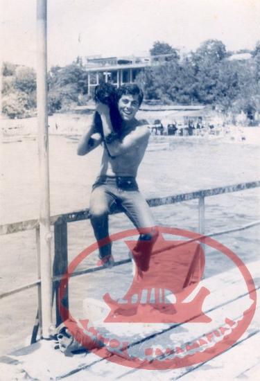 A young man with his dog sitting on the railing of the Kouri pier