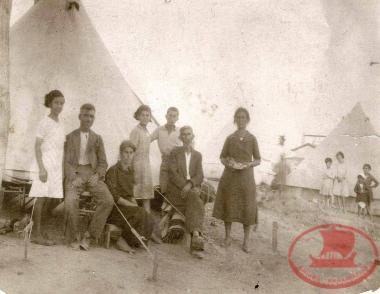 A refugee family in front of the tent given to them by the Greek government