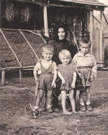 Woman and children photographed in front of dried tobacco
