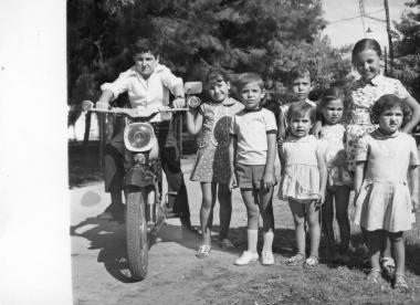 A group of children is photographed with a vintage motorcycle