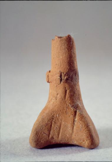 Πήλινο ειδώλιο γυναικείας μορφής σχηματοποιημένο με χάντρα στο λαιμό. Από τη Θεσσαλία.