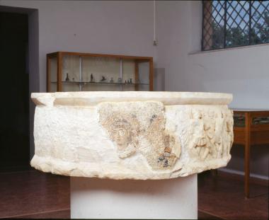 Μαρμάρινο κυλινδρικό βάθρο ανδριάντα με ανάγλυφη παράσταση αμαζονομαχίας. Την παράσταση αντικατέστησαν σε ένα μέρος οι χριστιανοί με ψηφιδωτό που εικονίζει δύο μορφές σε προτομή μέσα σε εγκόλπια.