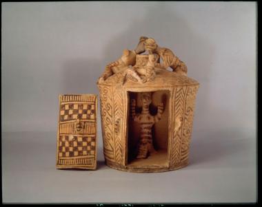 κυκλικός οικίσκος με θύρα που κλείνει με θυρόφυλλο και στο εσωτερικό καθιστή μορφή θεάς με υψωμένα χέρια