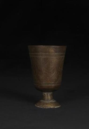 Χάλκινο κύπελο με πόδι και εγχάρακτο φυτικό διάκοσμο.