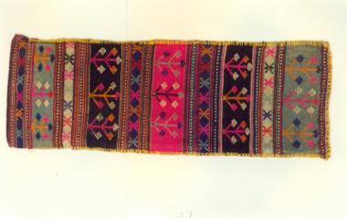 Στενόμακρη υφαντή μαξιλαροθήκη διακοσμημένη με πολύχρωμα σχηματοποιημένα γεωμετρικά θέματα