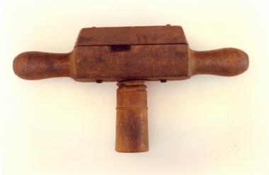 Ξύλινο εργαλείο αποτελούμενο από ένα κάθετο κυλινδρικό στοιχείο με πλατιά κεφαλή, στην οποία είναι προσαρμοσμένες δύο λαβές