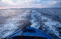 Βάρκα που σέρνει μικρότερη, το σούρουπο μετά το ψάρεμα, ανοικτά των Μουδανιών