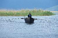 Ψαράς με τη βάρκα του στη λίμνη Μικρή Πρέσπα