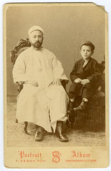 Φωτογραφία άνδρα με οθωμανική ενδυμασία και μικρό παιδί σε φωτογραφ είο της Κωνσταντινούπολης