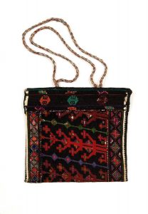 Cross stitch embroidery on canvas, stylized floral and multicoloured pattern with geometric borders on black background.
