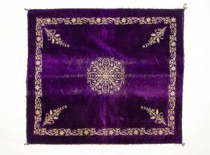Wrapper, purple velvet square with laid and couched gold embroidery, central floral ornament, corner motifs and scrolling foliate border.