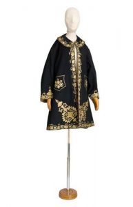 Short woman's black coat with gold embroidery.