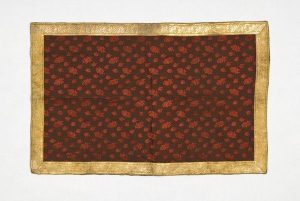 Brown cotton with woven-in pomegranate pattern and gold trimmings, possibly used as tablecloth.