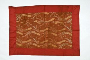 Rust brown silk with woven floral scroll pattern, probably made from a garment, with wine red satin borders.