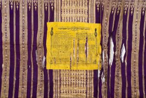 Yellow cotton panel with black printed text for Kiddush on Shabbat and holidays, printed by publishing house Joseph Schlesinger, Vienna, attached to purple and cream striped silk textile, possilby used as tablecloth or wall hanging.