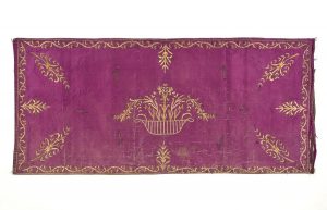 Purple silk with gold embroidery in couching technique, central flower vase and foliate border.