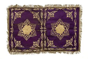 Dark purple silk with gold embroidery, symmetric commposition of two ornaments with corresponding corner motifs and foliate border, like the type used for the Brit Milah or the honorary seat of the Hatan Torah (Bridegroom of the Torah) in the Jewish Community of Ioannina.