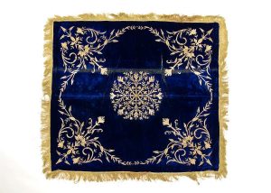 Dark blue velvet with laid and couched gold embroidery, central floral ornament and corner motifs, edged with gold fringe trim, used for Brit Milah ceremony.