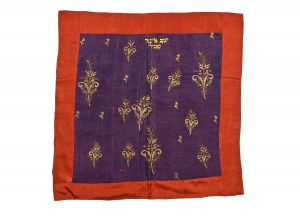 Reader's desk cover or Torah cover, purple silk square centrepiece with laid and couched gold embroidery, in secondary use, bordered by maroon silk stripes, gold embroidered inscription, dedicated in the name of Jacob Eliezer Kabeli, Trikala.