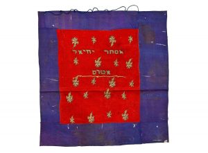 Tik (Torah case) wrapper, red silk centrepiece with laid and couched gold embroidery, in secondary use, bordered with dark blue silk, gold embroidered inscription, dedicated in the name of Esther Yehiel Atras.